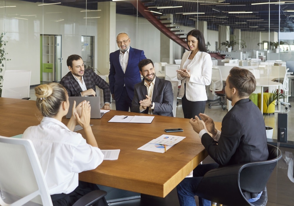 Réussite et Collaboration : Équipe Applaudissant en Réunion Équipe de bureau applaudissant joyeusement autour d'une table lors d'une réunion de succès en entreprise.